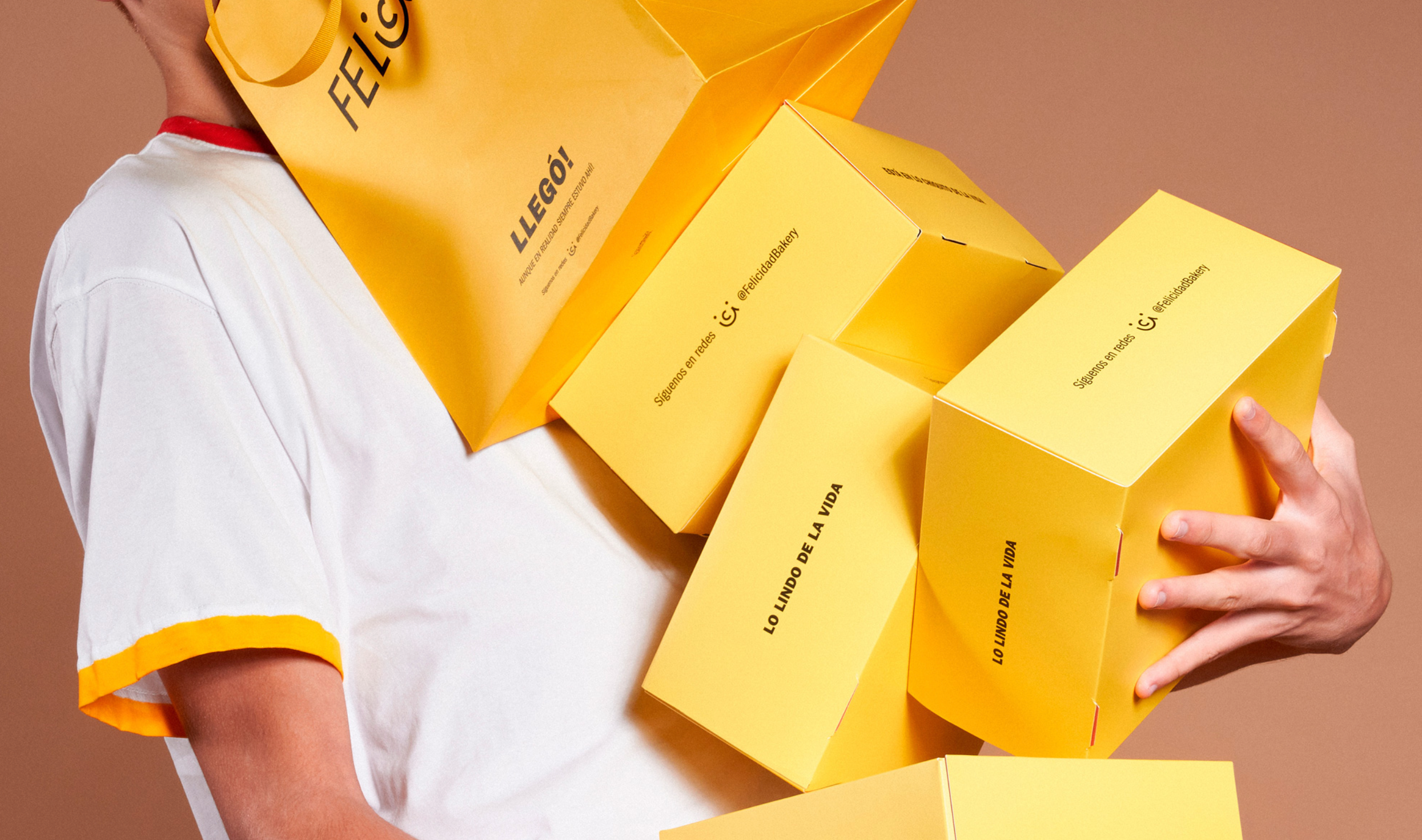 A man holding four yellow packaging boxes and a shopping bag